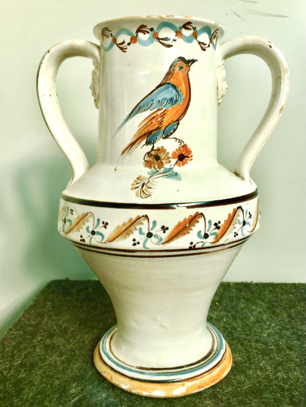 Doppelhenkelvase aus Majolika mit Maskaronen, verziert mit stilisierten floralen und vegetabilen Motiven und einem Vogel. Hergestellt in Grottaglie oder Martina Franca, Apulien.