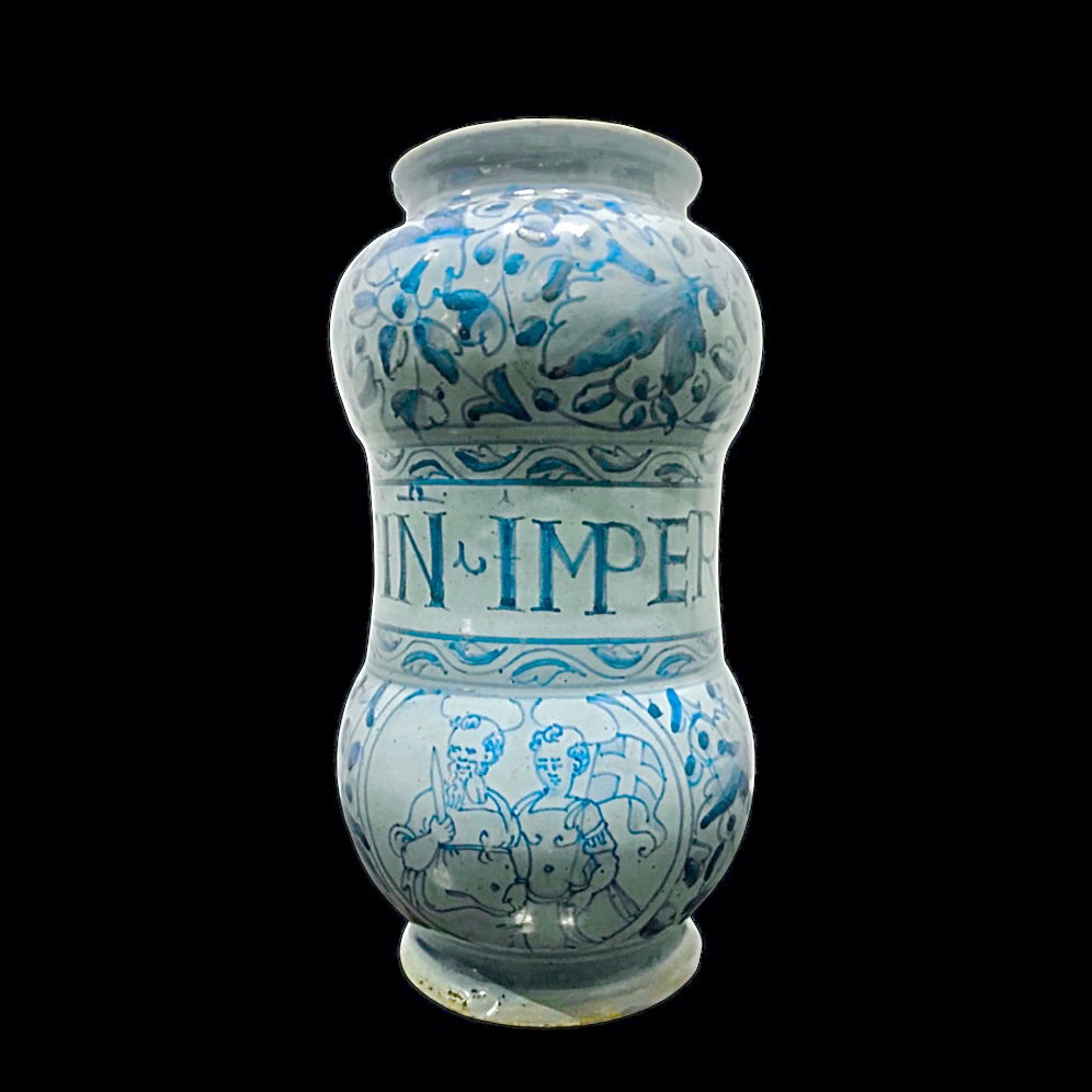Barrel-shaped albarello in 'berettino' majolica with vegetal and floral decorations, and a medallion depicting two crusaders. Rome. Cm 23x13.