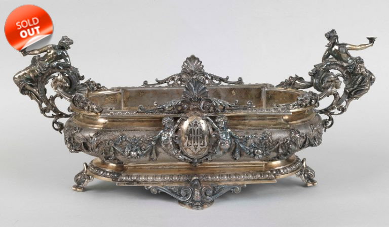 Centerpiece in embossed and chiseled silver with female figures and cherubs, and the coat of arms of the Torlonia family in the center.