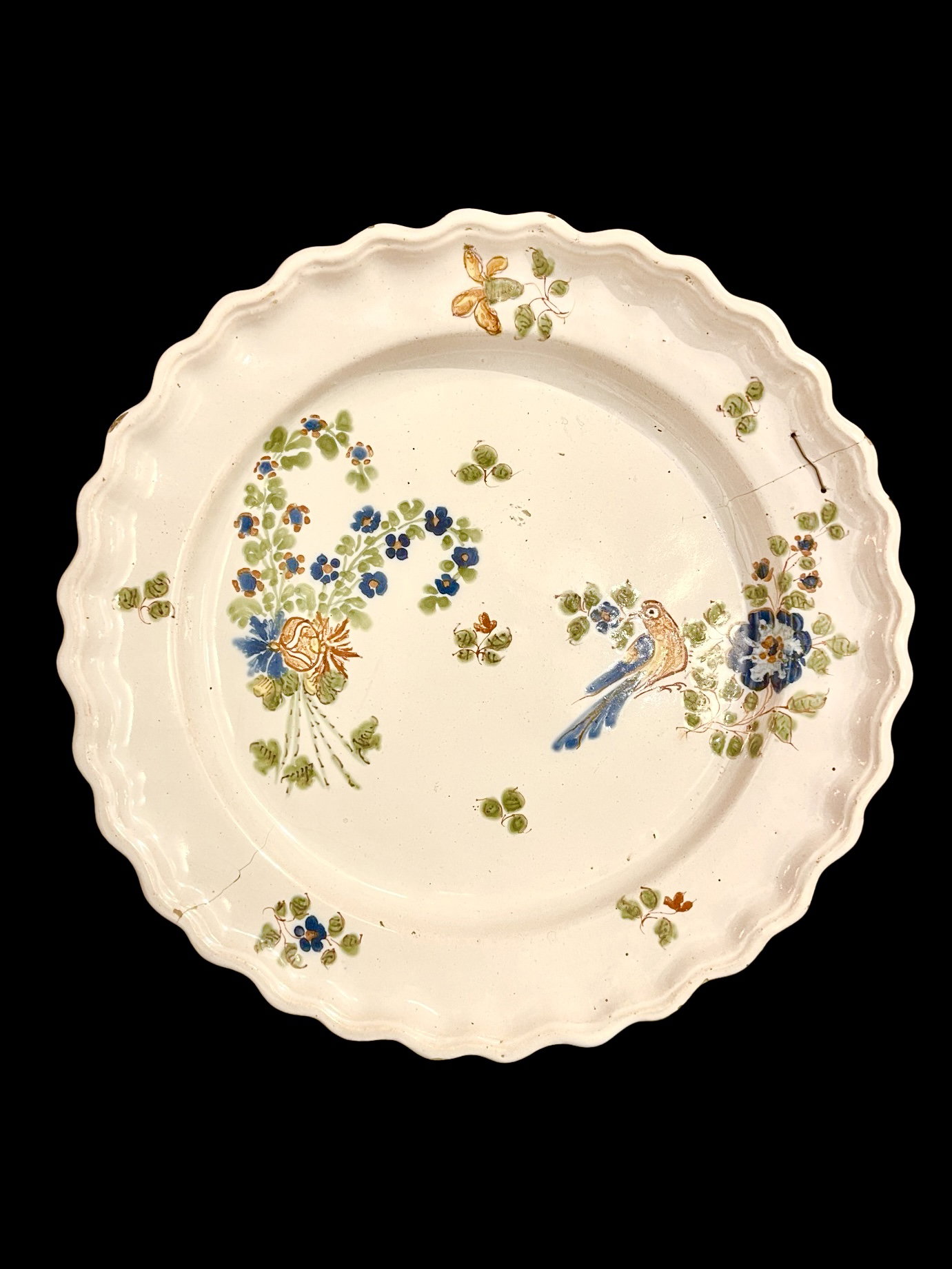 Plato de mayólica con decoración floral y de pájaro, con un ramillete de tallos floridos colgantes. Fabricado por Dallari, Sassuolo.