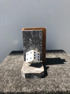 Coppia di fermalibri in marmo raffiguranti dadi da gioco.