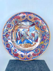 Grande piatto in maiolica a lustro con tesa decorata a motivi vegetali e rocaille e scena istoriata con personaggi al centro.Manifattura dì Alfredo Santarelli.Gualdo Tadino.
