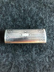 Silver matchbox and cigar clipper with geometric engravings and leaf patterns.
