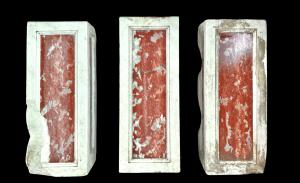 Three architectural elements in marble with a white frame and a variegated red central section.