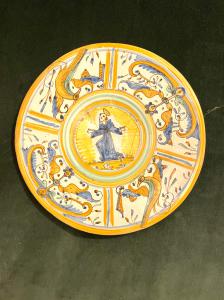 Piatto-tagliere in maiolica con decoro a quartieri a raffaellesche  e tondo centrale con figura di Santo.Manifattura di Deruta.