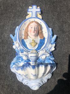 Weihwasserbecken mit Pflanzenmotiven und einem Tondo, das den jugendlichen Jesus darstellt.