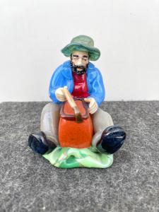 Glasskulptur eines sitzenden Mannes mit Korb. Böhmen.