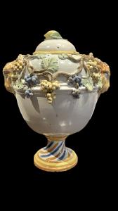 Majolica vase with grapevine motif in relief, handles in the shape of ram's heads, and a lid with a lemon-shaped knob. Dallari manufacture, Sassuolo.