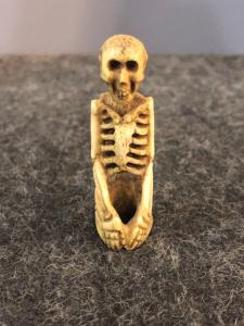Small sculpture depicting a kneeling skeleton made from bone.