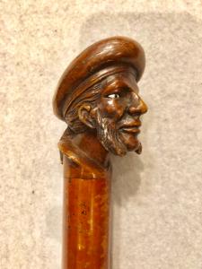 Bastone con pomolo in legno raffigurante figura maschile con basette e cappello.